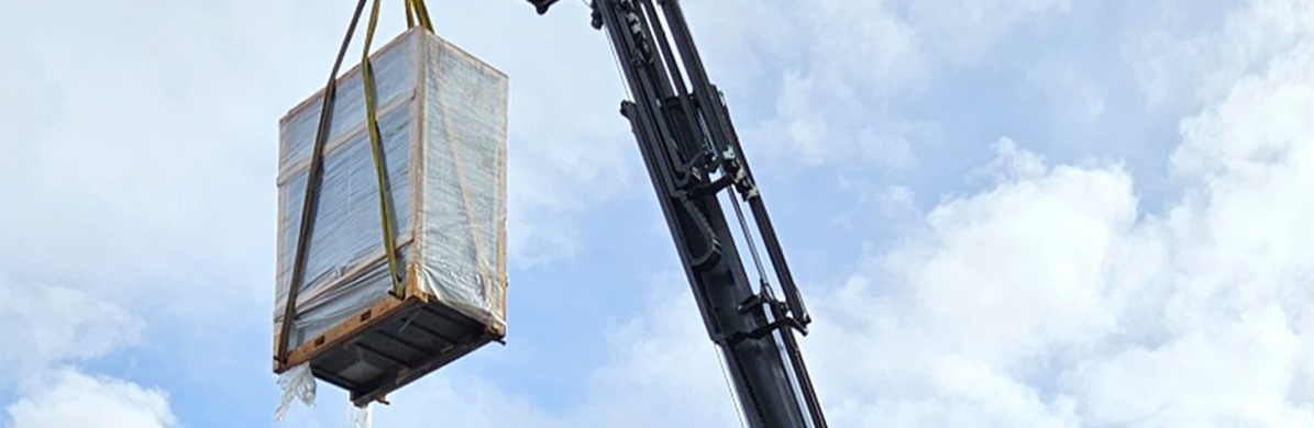 Rieger Metallveredlung Blog - Our heat exchanger - efficient and climate-neutral - New heat exchanger is placed in the company building with the help of a crane